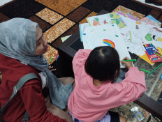 Life after divorce: Rizkynia Nabila (left) accompanies her daughter as she draws on June 20, 2026, in Jakarta. Nabila is among several single mothers who say court-ordered child support has been paid inconsistently following their divorce.