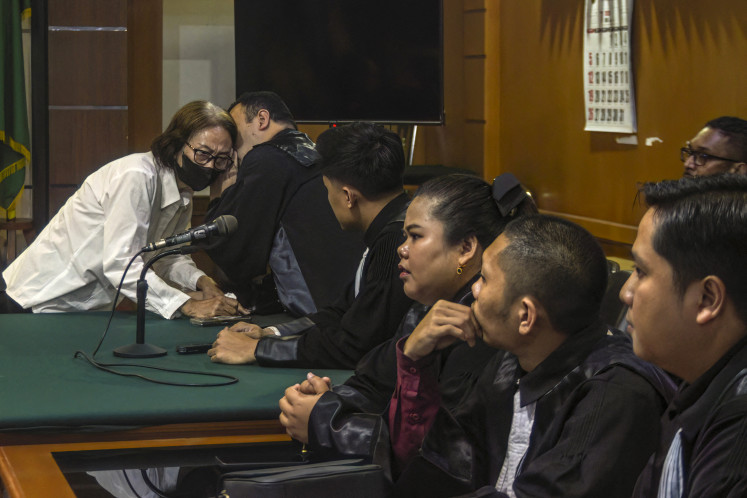 A defendant speaks to her lawyers during a trial in a baby trafficking case at the Bandung District Court in Bandung, West Java, on July 21, 2026. A woman who led a baby trafficking ring in Indonesia was sentenced July 21 to seven years in prison, a judge said. 