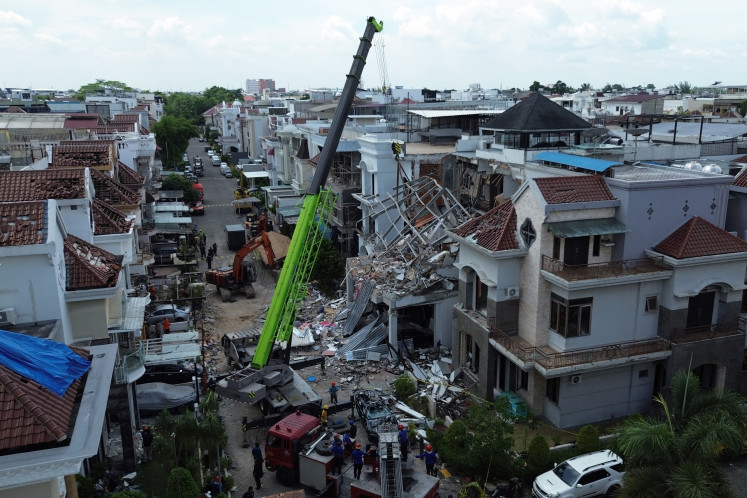 Rescue workers operate heavy equipment during a search for victims following an explosion at the Grand Polonia residential complex in Medan, North Sumatra, on July 21, 2026. According to the Medan Police, the explosion is believed to have been caused by a gas leak.