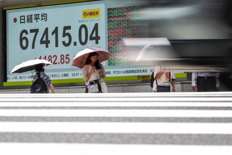 Pedestrians walk past an electronic quotation board displaying the Nikkei Stock Average on the Tokyo Stock Exchange in Tokyo on July 22, 2026.