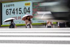 Pedestrians walk past an electronic quotation board displaying the Nikkei Stock Average on the Tokyo Stock Exchange in Tokyo on July 22, 2026.