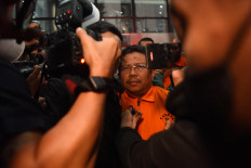 West Lombok Regent Lalu Ahmad Zaini (center) walks toward a detention vehicle after questioning at the Corruption Eradication Commission (KPK) headquarters in Jakarta on July 21, 2026. The KPK has detained Zaini, PT Air Minum Giri Menang president director Sudirman and PT Meconel Sistim Instrument president director Alvonsus Gani following a sting operation the previous day over alleged corruption involving conflicts of interest in government procurement, procurement bribery and gratuities in the West Lombok administration. 
