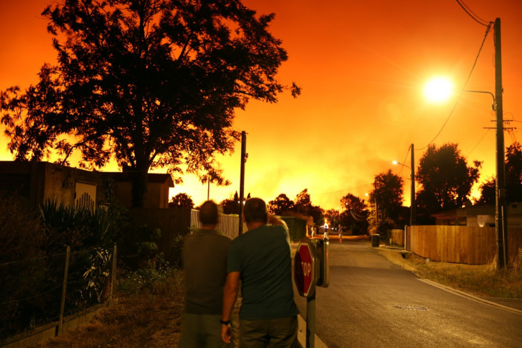 Residents look at the sky illuminated by wildfires in Le Porge, south-western France early on July 23, 2026. A fast-moving wildfire has burned 900 hectares north of Arcachon Bay in southwestern France, forcing the evacuation of more than 4,000 residents and tourists.