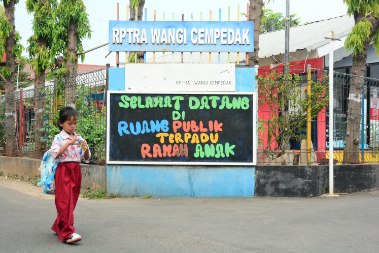 An elementary school pupil walks past the Wangi Cempedak integrated child-friendly public space (RPTRA) in East Jakarta on July 24, 2026.