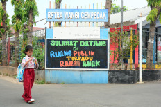 An elementary school pupil walks past the Wangi Cempedak integrated child-friendly public space (RPTRA) in East Jakarta on July 24, 2026.