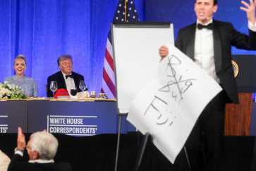 United States President Donald Trump (center) looks on next to White House Press Secretary Karoline Leavitt (left) as mentalist Oz Pearlman performs at the White House Correspondents' Association (WHCA) Dinner at the Waldorf Astoria hotel in Washington, D.C., the US, on July 24, 2026. The gala dinner was rescheduled from April after it was interrupted when a man tried to force his way through security and fired a shotgun, 