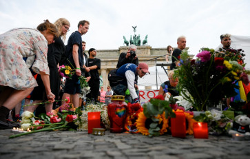 Mourners place bouquets of flowers on July 26, 2026 in front of landmark Brandenburg Gate during to a so-called &ldquo;community mourning&ldquo; one day after the car ramming attack on people on the outskirts of Berlin's Christopher Street Day (CSD) parade on late July 25, 2026, killing one person and injuring 16 in the Tiergarten park. 