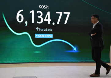 A man walks past an electronic screen showing South Korea's benchmark stock index (KOSPI) in a foreign exchange dealing room at the Hana Bank headquarters in Seoul on July 28, 2026.