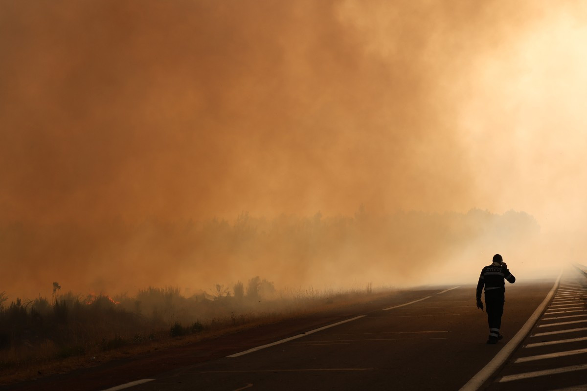 A firefighter walks on a road on the edge of a burning area in Ares on July 26, 2026 as a wildfire has been ravaging the forest north of the Arcachon Basin (Gironde) since July 22. 