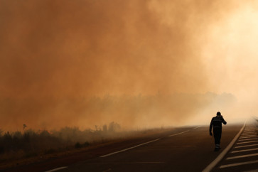 A firefighter walks on a road on the edge of a burning area in Ares on July 26, 2026 as a wildfire has been ravaging the forest north of the Arcachon Basin (Gironde) since July 22. 