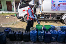 An Indonesian Red Cross (PMI) volunteer fills residents&rsquo; jerrycans with clean water in Batangan village, Bangkalan regency, East Java on July 21, 2026, as residents struggled to access groundwater in their homes due to a prolonged dry season linked to this year's El Nino weather phenomenon.