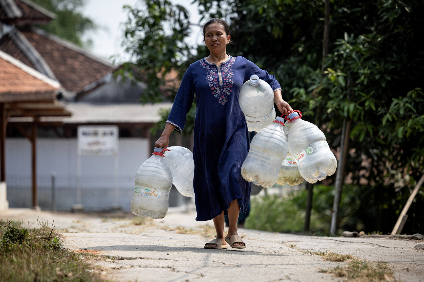 A woman carries water containers to collect free clean water distributed by the regional disaster agency in a drought-hit area during the dry season, amid forecasts that El Ni&ntilde;o may contribute to drier-than-normal conditions, in Rido Galuh village, Bekasi regency, West Java on July 16, 2026.
