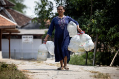 A woman carries water containers to collect free clean water distributed by the regional disaster agency in a drought-hit area during the dry season, amid forecasts that El Ni&ntilde;o may contribute to drier-than-normal conditions, in Rido Galuh village, Bekasi regency, West Java on July 16, 2026.