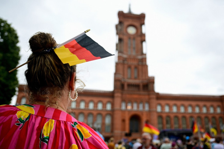 A supporter of the far-right Alternative for Germany (AfD) party wears a German flag in her hair as she attends a campaign rally in front of the Berlin City Hall on June 29, 2026. 