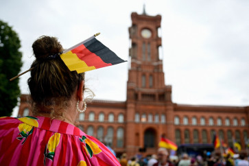 A supporter of the far-right Alternative for Germany (AfD) party wears a German flag in her hair as she attends a campaign rally in front of the Berlin City Hall on June 29, 2026. 
