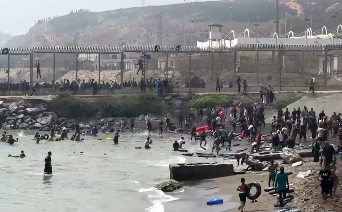 This video frame grab obtained from an AFP video shows migrants reaching the shore of Spanish north African exclave of Ceuta, after swimming around the border fence between Morocco and Spain, in Ceuta on July 30, 2026. Hundreds of migrants entered the Spanish north African exclave of Ceuta today, AFP reporters saw, many of them having swum by sea around the frontier fence. 