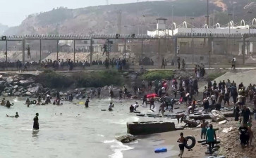 This video frame grab obtained from an AFP video shows migrants reaching the shore of Spanish north African exclave of Ceuta, after swimming around the border fence between Morocco and Spain, in Ceuta on July 30, 2026. Hundreds of migrants entered the Spanish north African exclave of Ceuta today, AFP reporters saw, many of them having swum by sea around the frontier fence. 