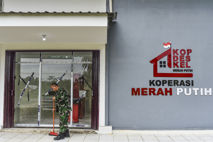 A soldier sweeps the entrance to a Red and White Cooperatives building in Suka Damai village, Muaro Jambi regency, Jambi on July 22, 2026.