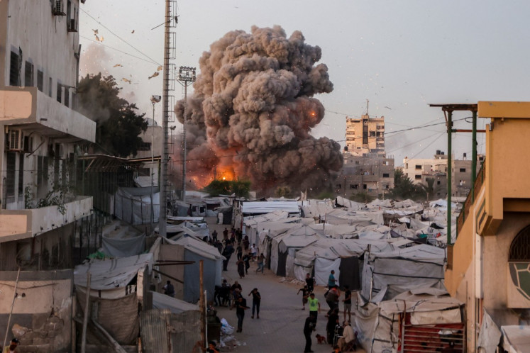Palestinians run for cover as smoke and fire rise during an Israeli strike on the the Al-Muttaqin Mosque in Gaza City on July 28, 2026. Gaza remains gripped by daily violence, with both the Israeli military and Hamas accusing one another of violating the truce in effect since Oct. 10.