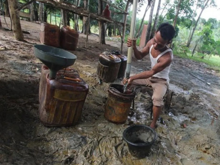 A worker pours crude oil using traditiona equipment on May 31, 20215, in Telaga Said village, Sei Lepan in Langkat regency, North Sumatra. The village has about 100 old oil wells previously operated by state-owned oil and gas company PT Pertamina. 