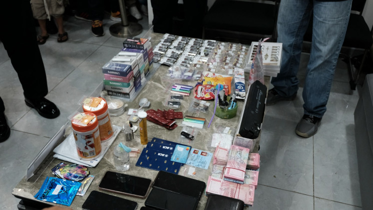 Law enforcement officers gather around a table full of pieces of evidence confiscated from a Malaysian-led drugs syndicate during a joint press conference on July 31 in Sakura Garden, Batu Ampar area in Batam, Riau Islands. A joint operation consisting of officers from the National Narcotics Agency and the Customs and Excise Directorate General raided four locations in Batam and arrested six Indonesians. 