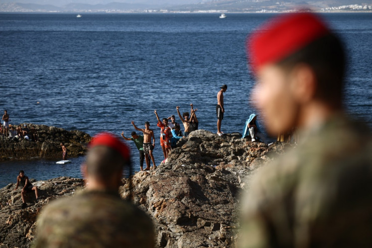 Members of the Spanish Army's 'Regulares' infantry forces watch a group of migrants near the border post of the Spanish enclave of Ceuta on August 2, 2026. At least 72 people died during last week's mass influx of migrants into Spain's Ceuta enclave, when tens of thousands of people mostly swam around the border post from Morocco, local officials said today. Most of the estimated 60,000 people who rushed into Spain's north African territory have returned to Morocco since the territory's largest mass migrant crossing.