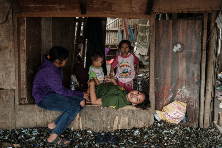 A woman lies on a wooden frame above a floor piled with green mussel shells on Sept. 20, 2025, in Cilincing, North Jakarta. Green mussels are widely harvested in Jakarta Bay, but there are concerns that pollution from factories and households may accumulate in them, including heavy metals and other contaminants.