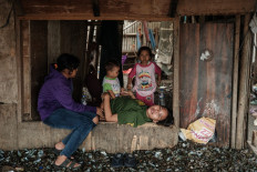 A woman lies on a wooden frame above a floor piled with green mussel shells on Sept. 20, 2025, in Cilincing, North Jakarta. Green mussels are widely harvested in Jakarta Bay, but there are concerns that pollution from factories and households may accumulate in them, including heavy metals and other contaminants.