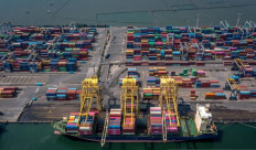 Export oriented: Using a rubber-tired gantry crane, port workers load export-bound containers onto a vessel flying a Portuguese flag on June 24, 2025, at Tanjung Mas port in Semarang, Central Java. 