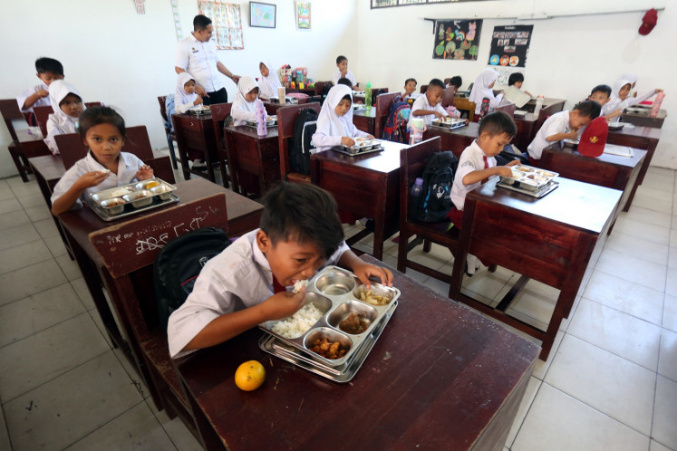 Students eat meal packages disbursed under the free nutritious meal program on Tuesday at SDN 106162 state elementary school in Deli Serdang regency, North Sumatra. 