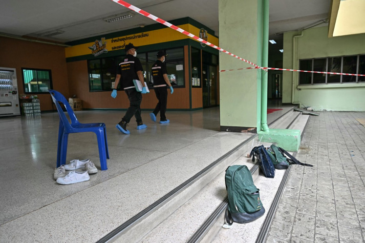 Students' belongings are left at the scene of a school shooting as forensic police walk past in Bang Kruai district, Nonthaburi province, north of Thailand's capital Bangkok, on August 7, 2026. A teenage suspect killed his grandparents before shooting dead at least six more people at a school near Bangkok on August 7, police said. 