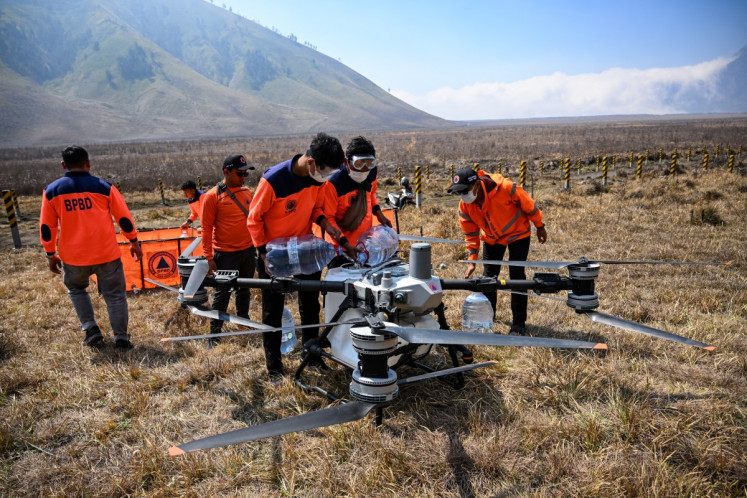 Officials from the East Java Provincial Disaster Management Agency fill a drone&rsquo;s water tank to battle a wildfire in the Bromo Tengger Semeru National Park near Mount Bromo in Probolinggo, East Java, on August 6, 2026.