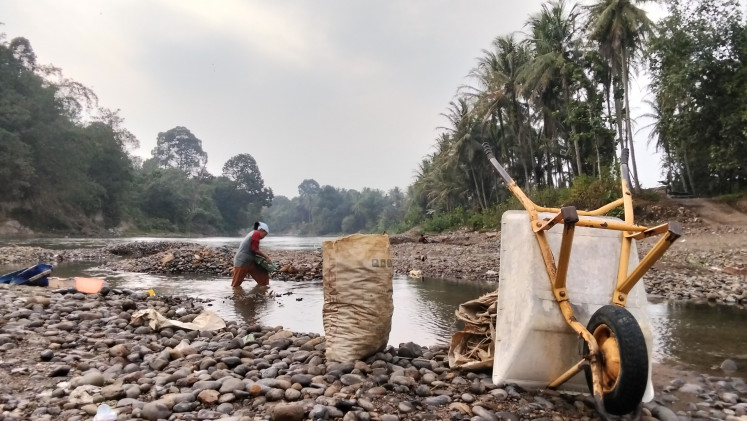 Asnili, a resident of Pulau Panggung village, Muara Enim regency, South Sumatra, searches for gravel in the Enim River to earn a living on July 21, 2026.