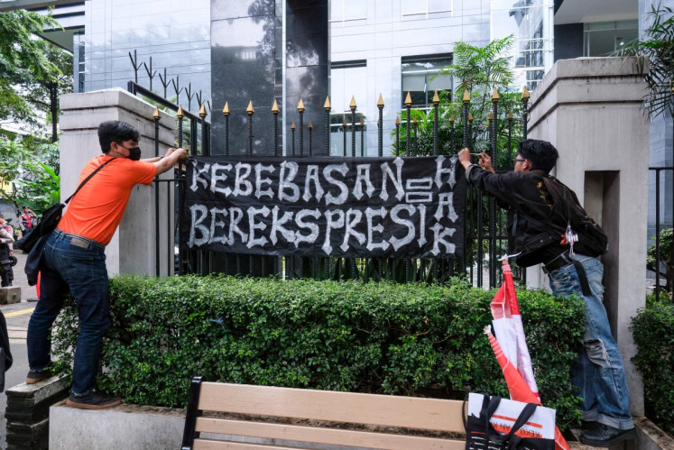 Two activists install a banner reading &ldquo;Freedom of expression = a right&rdquo; on a fence surrounding the Central Jakarta District Court on March 6, 2026, when the court acquitted activists Delpedro Marhaen Rismansyah, Khariq Anhar, Muzaffar Salim and Syahdan Husein in their trial for incitement in relation to the anti-government protests in August-September 2025.