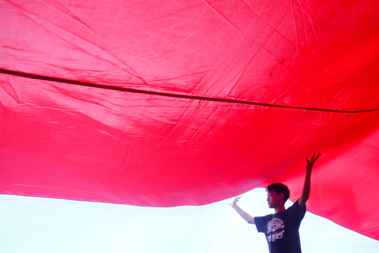 A participant unfurls a red-and-white flag on Sunday while taking part in the Red and White Parade along Jl. Jenderal Sudirman in Bogor, West Java. 