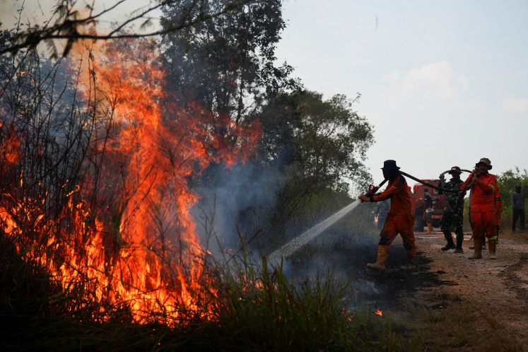 Firefighters and military personnel spray water on Aug. 9, 2026, in an attempt to extinguish a forest fire in Ogan Ilir regency, South Sumatra.
