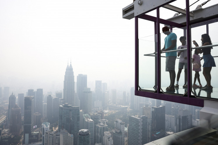 Tourists look at the skyline on Aug. 12 in Kuala Lumpur, as the city lies shrouded in haze from wildfires in Borneo. 