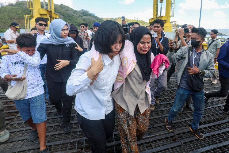 A distressed woman is supported by a rescue team member upon arriving at Lembar port in West Lombok on August 12, 2026. A navy vessel and other ships rushed in on August 12 to rescue over 100 people from a ferry on fire off the tourist island of Bali, officials said, in the second such incident in days.