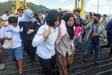 A distressed woman is supported by a rescue team member upon arriving at Lembar port in West Lombok on August 12, 2026. A navy vessel and other ships rushed in on August 12 to rescue over 100 people from a ferry on fire off the tourist island of Bali, officials said, in the second such incident in days.