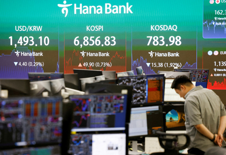 A currency dealer works as an electronic board displays the Korea Composite Stock Price Index (KOSPI), the exchange rate between the US dollar and South Korean won and the Korea Securities Dealers Automated Quotations (KOSDAQ) at the dealing room of a bank in Seoul on July 14, 2026.
