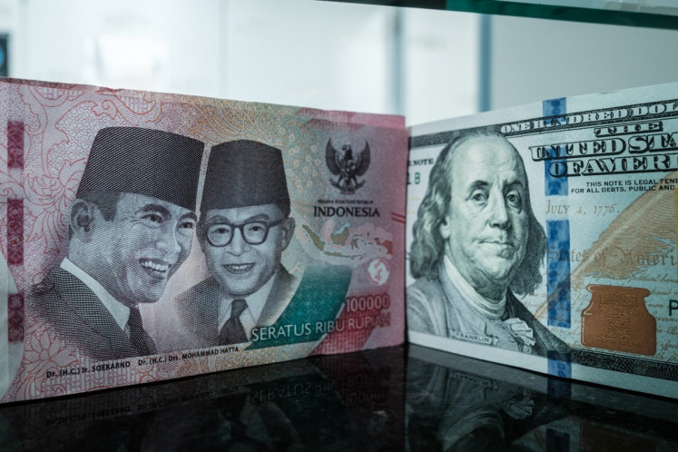 An Rp 100,000 banknote is pictured next to a US$100 banknote at a currency exchange office in Jakarta on June 4, 2026, after the rupiah weakened beyond Rp 18,000 per US$1 for the first time. 