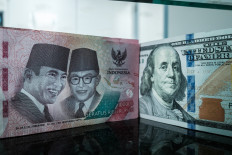 An Rp 100,000 banknote is pictured next to a US$100 banknote at a currency exchange office in Jakarta on June 4, 2026, after the rupiah weakened beyond Rp 18,000 per US$1 for the first time. 