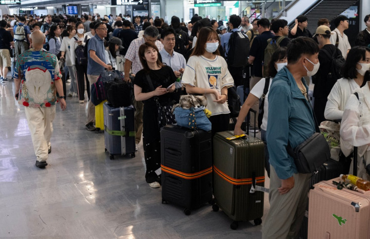 Passengers line up to enter the train station at the Narita International Airport in Narita, Chiba prefecture on August 14, 2026, after many of the train lines to the airport were closed. At least four people died in eastern Japan after unprecedented heavy rain that left thousands stranded at Narita airport overnight and snarled up roads and rail services, authorities said.