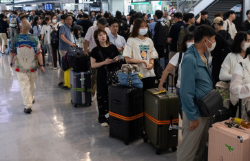 Passengers line up to enter the train station at the Narita International Airport in Narita, Chiba prefecture on August 14, 2026, after many of the train lines to the airport were closed. At least four people died in eastern Japan after unprecedented heavy rain that left thousands stranded at Narita airport overnight and snarled up roads and rail services, authorities said.