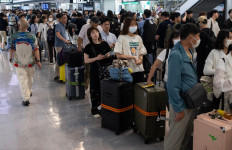 Passengers line up to enter the train station at the Narita International Airport in Narita, Chiba prefecture on August 14, 2026, after many of the train lines to the airport were closed. At least four people died in eastern Japan after unprecedented heavy rain that left thousands stranded at Narita airport overnight and snarled up roads and rail services, authorities said.