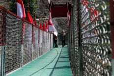 Two women walk across the Garuda Perintis Bridge after its inauguration on Aug. 13 in Malang, East Java. The 1.2-meter bridge above the Brantas River was built by the Malang District Military Command and local communities to ease pedestrian and small vehicle mobility.