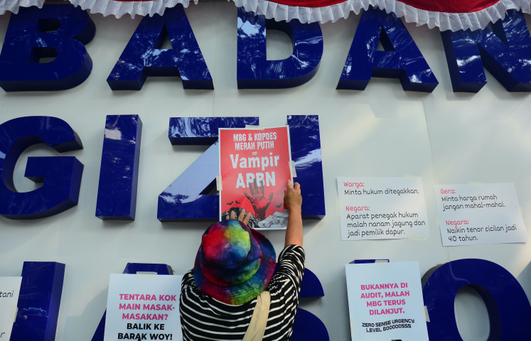 Participants in a protest by a civil society coalition known as MBG Watch display a poster reading &ldquo;Free Nutritious Meals and Red-and-White Cooperatives = Vampires of the State Budget&rdquo; outside the National Nutrition Agency (BGN) office in Central Jakarta on Aug. 14, 2026.
