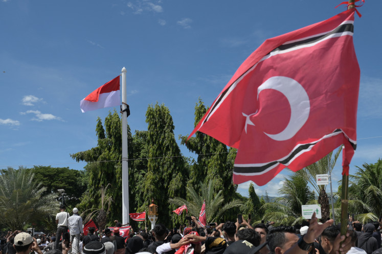 A man (top left) climbs a flagpole on Saturday as he attempts to raise a Free Aceh Movement flag alongside the Indonesian national flag during a rally outside the Baiturrahman Grand Mosque in Banda Aceh, Aceh province. Thousands of people gathered to mark the 21st anniversary of the Helsinki Memorandum of Understanding (MoU) peace agreement, which ended nearly three decades of conflict. The raising of the separatist-linked flag, although not explicitly banned by the 2005 peace deal, remains a highly controversial issue, with central government authorities often prohibiting its display.