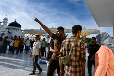 Angry protesters shout at soldiers as they remove a Free Aceh Movement (GAM) flag on Aug. 15, 2026, displayed alongside the Indonesian national flag during a rally at the Baiturrahman Grand Mosque in Banda Aceh, Aceh. Thousands of people gathered to mark the 21st anniversary of the Helsinki Memorandum of Understanding (MoU) peace agreement, which ended nearly three decades of conflict. The raising of the separatist-linked flag, although not explicitly banned by the 2005 peace deal, remains a highly controversial issue, with central government authorities often prohibiting its display.