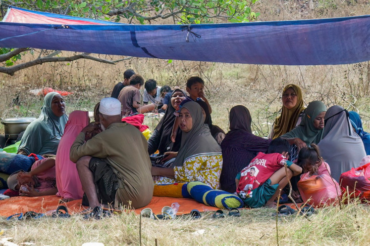 Villagers look on after spending the night in an open field in Nangahale village in Sikka, East Nusa Tenggara (NTT), on August 16, 2026, after a magnitude 7.7 earthquake off Indonesia's eastern Flores island. Rescuers combed through debris for survivors on August 15 after a powerful earthquake struck off Flores island, killing at least 47 people, according to disaster officials.